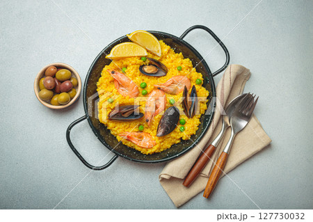 Spanish seafood Paella with shrimps, mussels, peas and lemon in a pan on grey rustic background top view 127730032