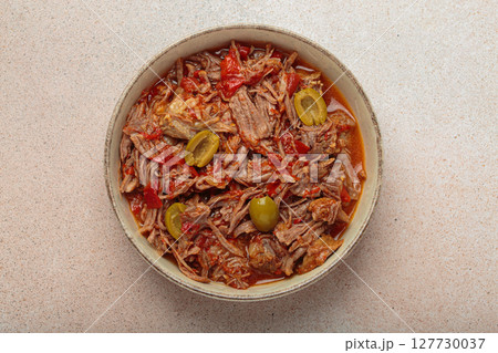 Ropa vieja with white rice, tomato sauce and green olives on a plate top view, traditional dish of Cuba 127730037