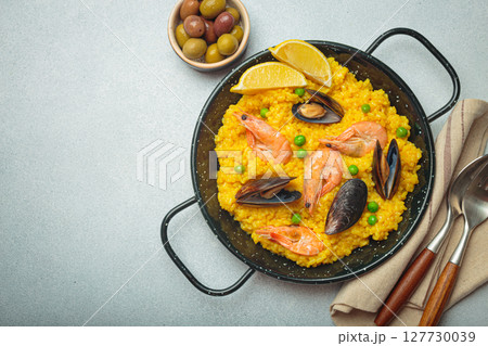 Spanish seafood Paella with shrimps, mussels, peas and lemon in a pan on grey rustic background top view, space for text 127730039