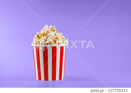 Classic red striped popcorn cardboard cup on Purple, violet background Classic red striped popcorn cardboard cup on Purple, violet background 127730312