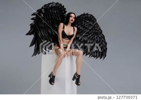 Woman in lingerie with striking black wings posing confidently Woman in lingerie with striking black wings posing confidently 127730371