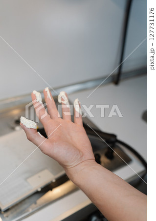 Vertical cropped shot of unrecognizable man holding moisturizing cream mixed with some white powder in hand, preparing skin treatment standing in kitchen setting, closeup. Concept of healthy lifestyle 127731176