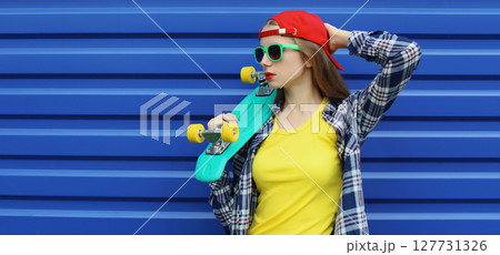Stylish young woman with skateboard, modern teenage girl posing on city street, colorful wall 127731326