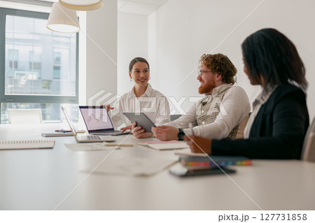 A team meeting occurs in a modern office with devices that enhance collaboration and productivity 127731858