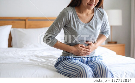 寝室で腹痛に苦しむ女性 127732814