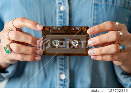 Woman holding vintage audio cassette tape in her hands 127732856