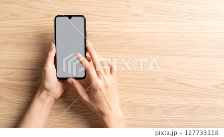 机上でスマートフォンを操作する女性の手 机上でスマートフォンを操作する女性の手 127733118