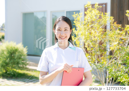 建物の前で微笑む女性看護師 127733704