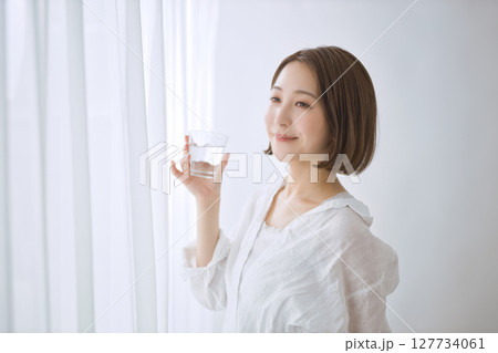 リビングで水を飲む若い女性 127734061