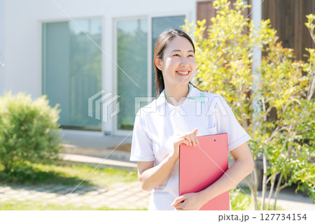 建物の前で微笑む女性看護師 127734154