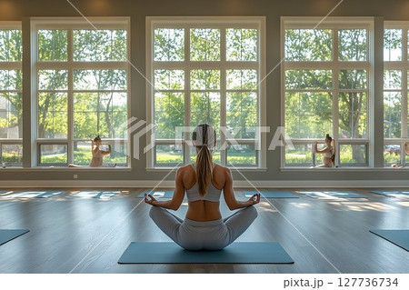Woman meditating in yoga pose by large window sunlight Woman meditating in yoga pose by large window sunlight 127736734