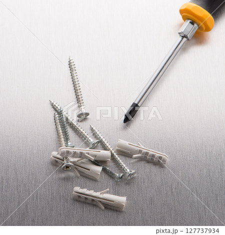 Screwdriver, screws and plastic dowels 127737934