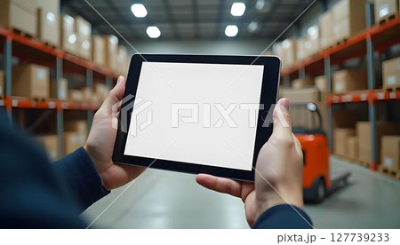 A warehouse environment showcases a man with a tablet, actively involved in inventory management or logistics activities 127739233