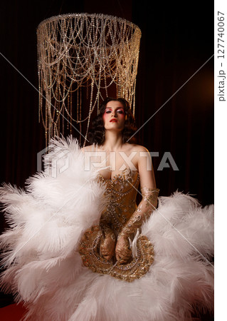 Young woman in vintage corset costume posing under chandelier on dark background 127740067