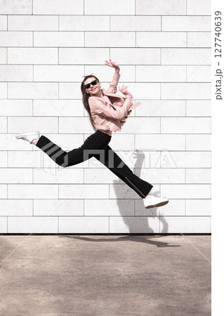 Beautiful woman jumping in brick wall background 127740639