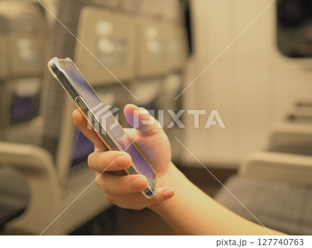 新幹線車内でスマホを見る男性の手元 新幹線車内でスマホを見る男性の手元 127740763