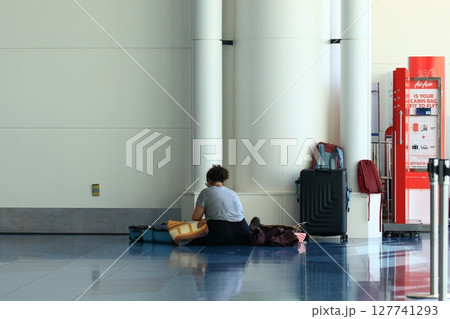 空港の出発ロビーでスーツケースの荷物を詰め替える外国人観光客 127741293