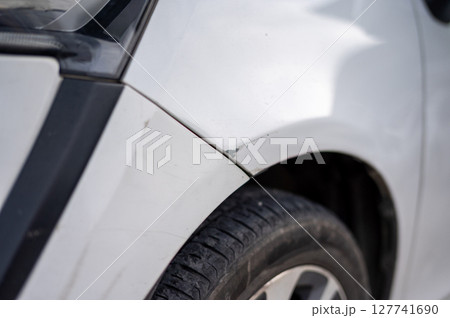 Chipped paint and slight dent on car fender above tire 127741690