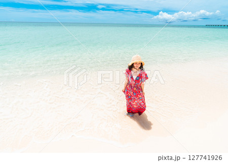 南国ビーチで波打ち際を歩くワンピース姿の若い女性 南国ビーチで波打ち際を歩くワンピース姿の若い女性 127741926