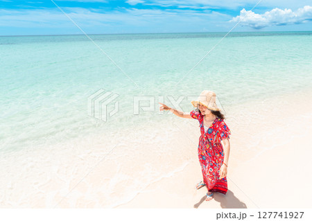 南国ビーチで波打ち際を歩くワンピース姿の若い女性 南国ビーチで波打ち際を歩くワンピース姿の若い女性 127741927