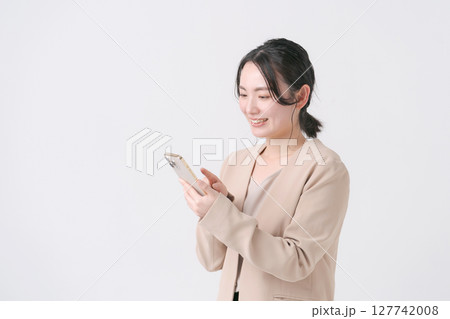 スマホを持つスーツ姿の20代女性 127742008