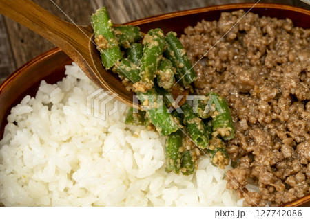 三食丼弁当を詰める そぼろ,いんげんの胡麻和え, 炒り卵をご飯に乗せる 127742086