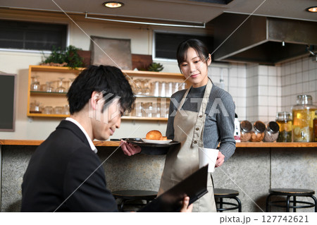 飲食店で男性客に食事の配膳をする女性店員 127742621