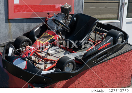 A small sports car on a pedestal in front of a karting center. 127743779