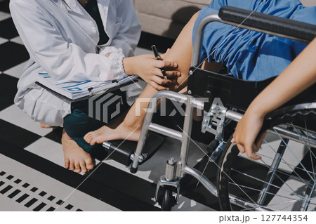 Physiotherapist checking knee of female patient stock Physiotherapist checking knee of female patient stock 127744354