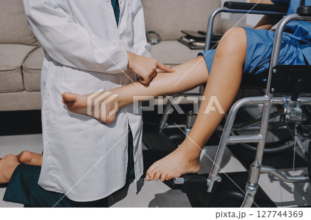 Physiotherapist checking knee of female patient stock 127744369