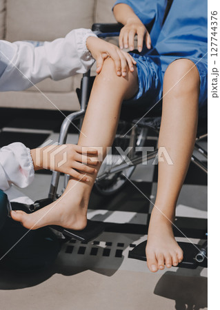 Physiotherapist checking knee of female patient stock Physiotherapist checking knee of female patient stock 127744376