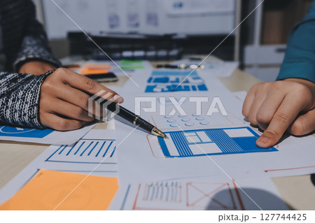 Group of young application developers analyzing uxui mobile app templates during a working meeting Group of young application developers analyzing uxui mobile app templates during a working meeting 127744425