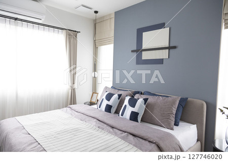 Stylish Bedroom in blue and white tone pillows setting. Cozy bedroom with art wall. Stylish Bedroom in blue and white tone pillows setting. Cozy bedroom with art wall. 127746020