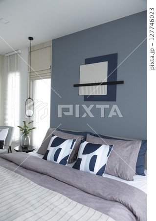 Stylish Bedroom in blue and white tone pillows setting. Cozy bedroom with art wall. Stylish Bedroom in blue and white tone pillows setting. Cozy bedroom with art wall. 127746023