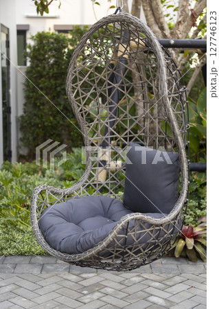 Rattan wicker cocoon garden swing chair hanged on frame. Recreation scene with a hammock-chair in the backyard of the house. Relax concept with hammock chair . Rattan wicker cocoon garden swing chair hanged on frame. Recreation scene with a hammock-chair in the backyard of the house. Relax concept with hammock chair . 127746123