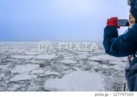 北海道網走市　流氷観光砕氷船おーろら号からの流氷の海面を写真に撮る観光客 127747165
