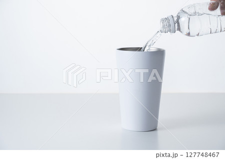 ステンレスタンブラーにペットボトルの水を注ぐ 127748467