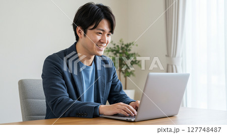 自宅でノートパソコンを使ってオンラインミーティングを行うビジネスマン 127748487