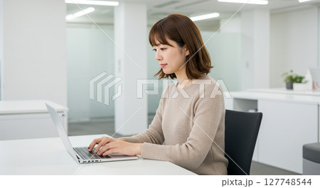 ノートパソコンで作業するカジュアルな服装の日本人女性 127748544