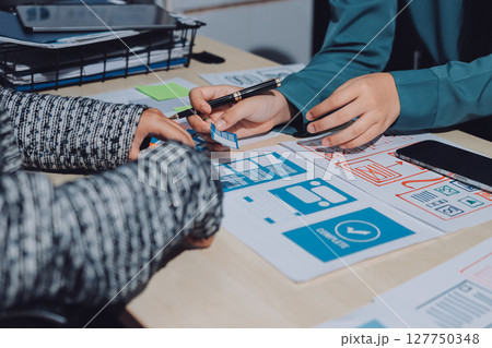 Group of young application developers analyzing uxui mobile app templates during a working meeting 127750348