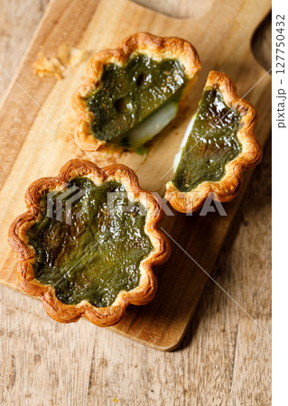 Closeup of Matcha and mochi Portuguese sweet dessert egg tart or Pastel de Nata on wooden board on wooden table. 127750432