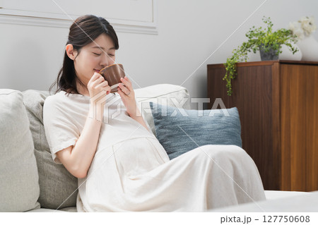ソファーで飲み物を飲む妊婦 ライフスタイルイメージ ソファーで飲み物を飲む妊婦 ライフスタイルイメージ 127750608