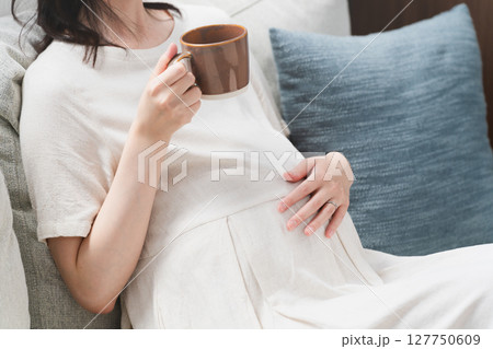 ソファーで飲み物を飲む妊婦 ライフスタイルイメージ ソファーで飲み物を飲む妊婦 ライフスタイルイメージ 127750609