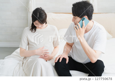 妊婦が破水してスマートフォンで電話をする夫　ライフスタイルイメージ 127750678