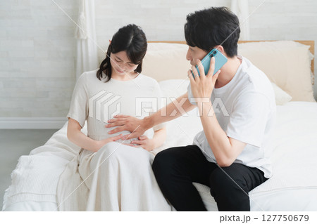 妊婦が破水してスマートフォンで電話をする夫　ライフスタイルイメージ 127750679