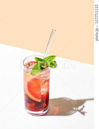 Refreshing cocktail with grapefruit, mint and ice in a glass on a white yellow background Refreshing cocktail with grapefruit, mint and ice in a glass on a white yellow background 127751115