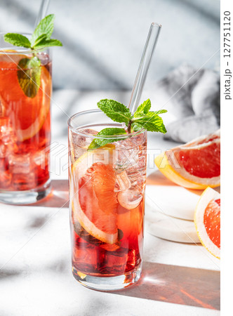 Two glasses of cocktail with grapefruit, mint and ice on a light trxtured background with shadow Two glasses of cocktail with grapefruit, mint and ice on a light trxtured background with shadow 127751120