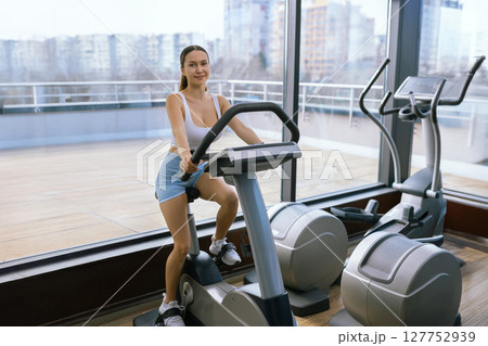 Attractive young woman at the gym riding on spinning bike. Healthy Lifestyle and Sport Concepts. Attractive young woman at the gym riding on spinning bike. Healthy Lifestyle and Sport Concepts. 127752939
