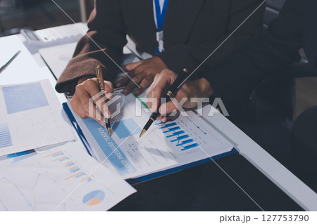 Focused young businessman signing agreement with skilled lawyer in eyeglasses. Concentrated financial advisor showing place for signature on paper contract document to male client at meeting in office Focused young businessman signing agreement with skilled lawyer in eyeglasses. Concentrated financial advisor showing place for signature on paper contract document to male client at meeting in office 127753790
