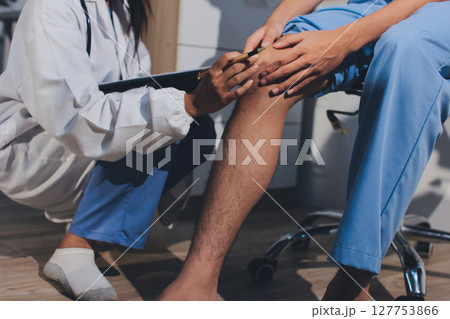 Physical therapist teaching a patient how to do exercises for his knee pain 127753866